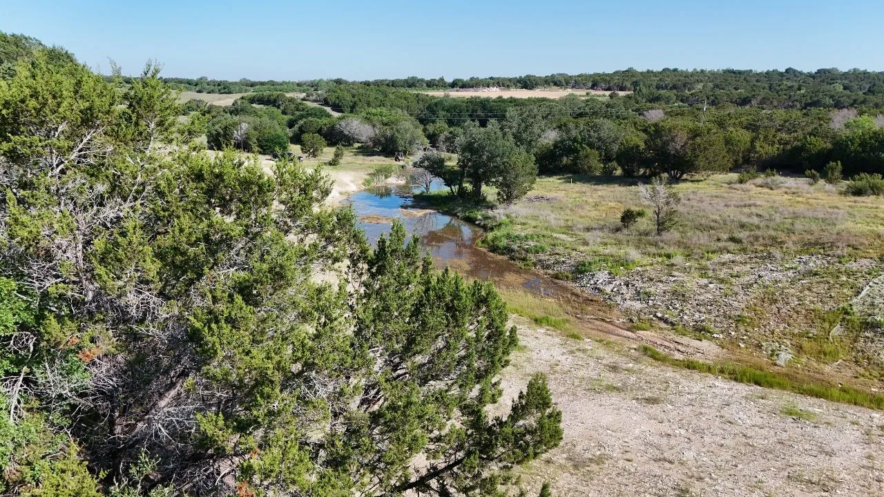 Expansive natural landscape featuring a winding waterway, mature trees, and varied terrain