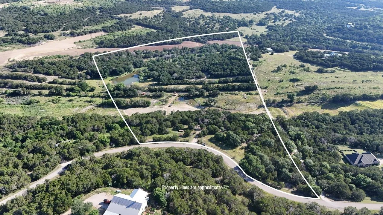 Expansive acreage featuring abundant trees, a visible pond, and direct road frontage