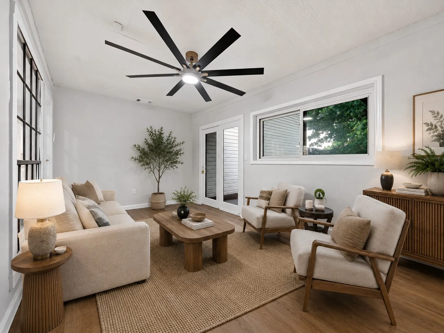 AI Staging: Spacious living area featuring wood-finish flooring, a large ceiling fan with integrated lighting, expansive windows, a sliding glass door, and a built-in wall-mounted cabinet