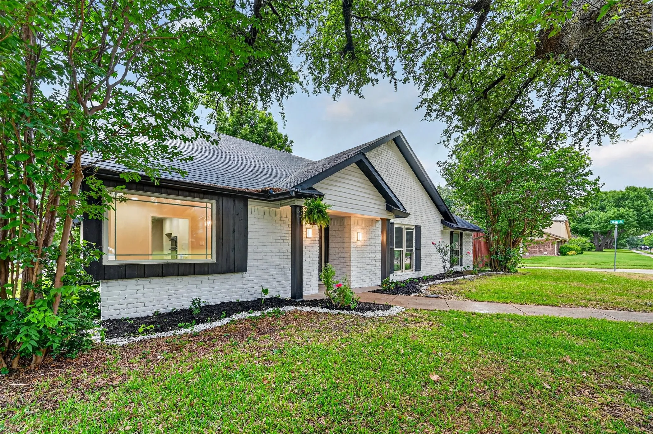 White painted brick exterior with black trim, a gabled roof, and dark shutters