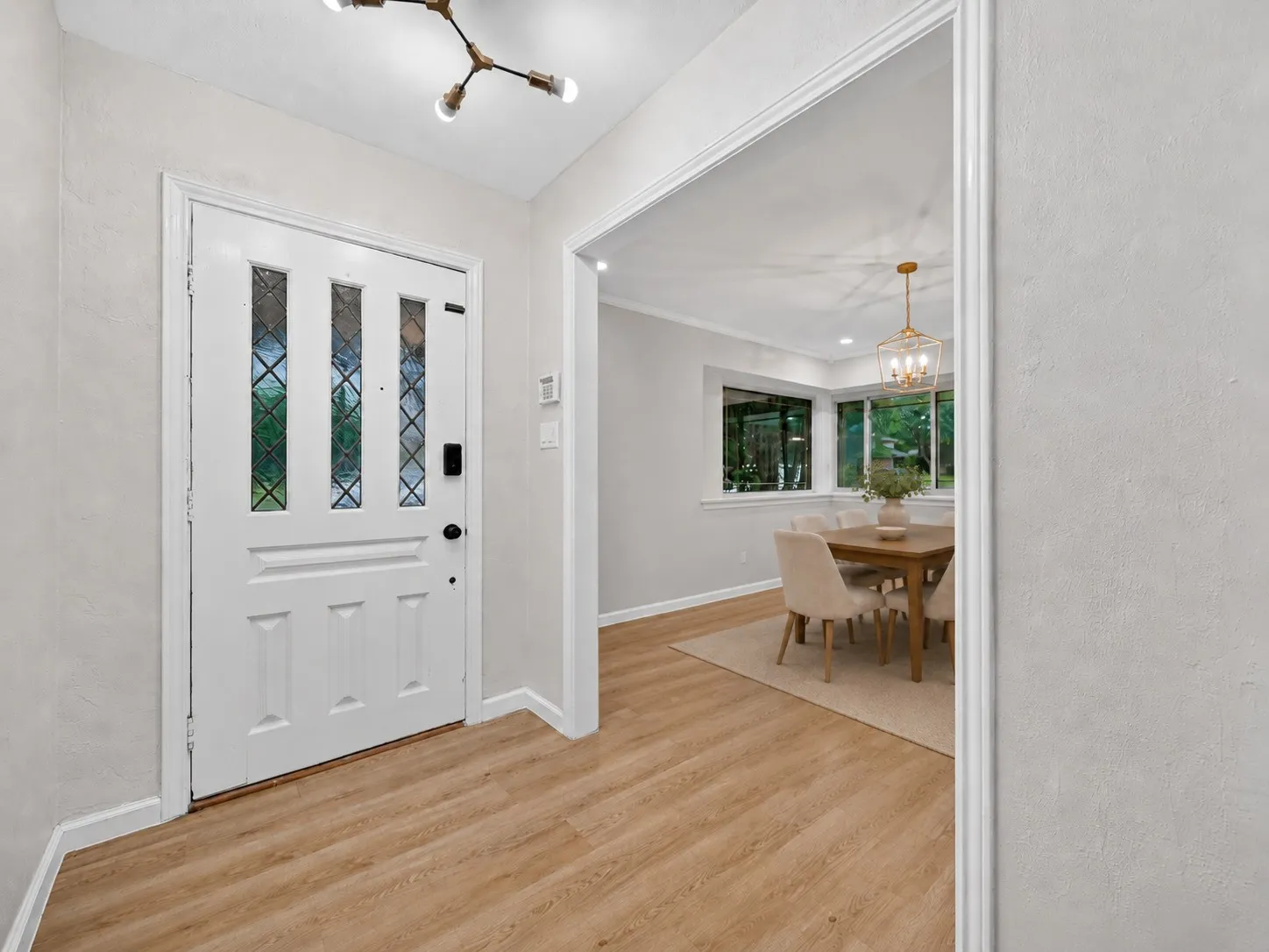 Entryway with wood-finish flooring, a white paneled door with leaded glass inserts, and a contemporary ceiling light fixture