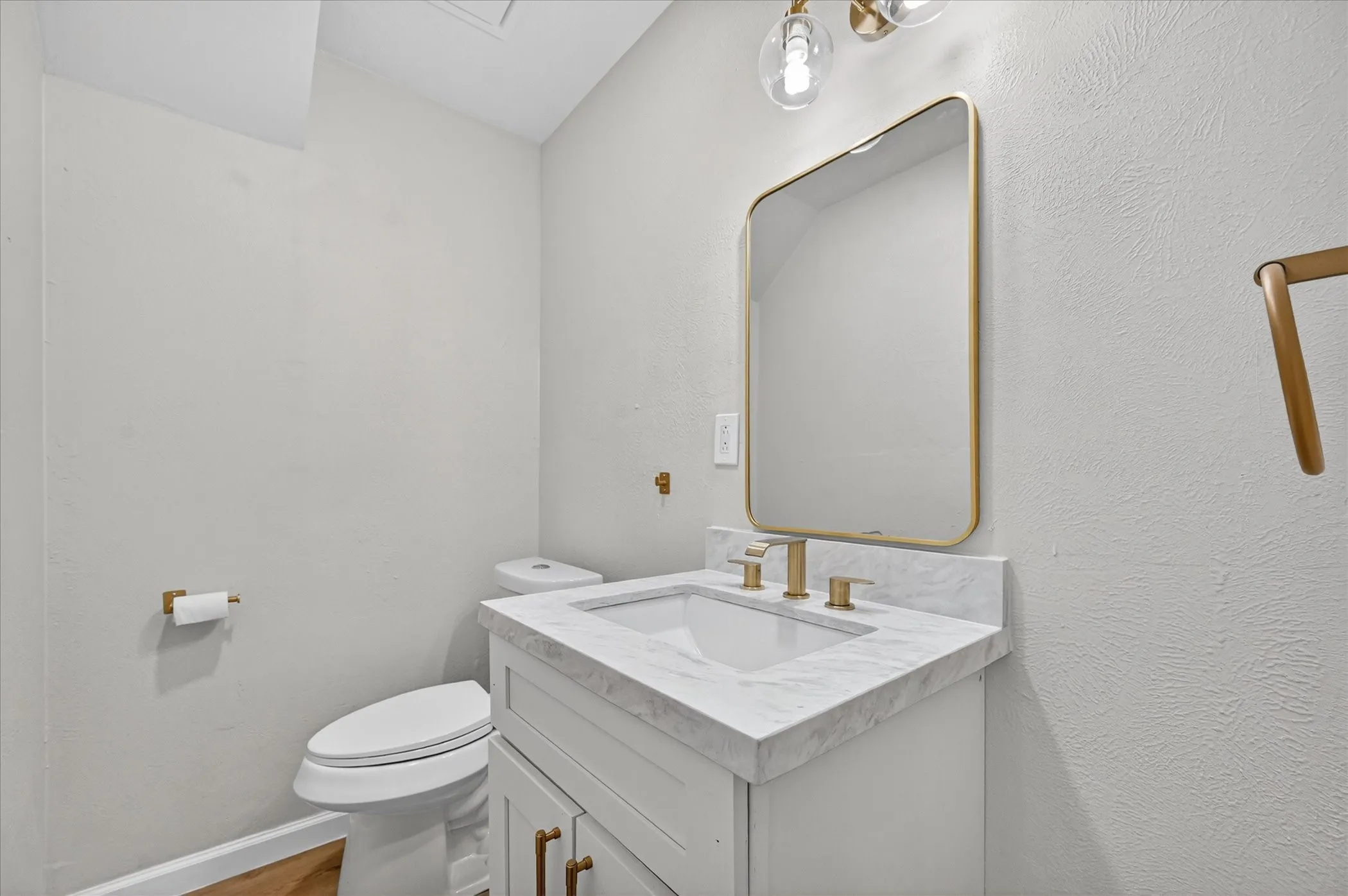 Bathroom vanity featuring a rectangular undermount sink, a light-toned countertop, and a gold-framed mirror