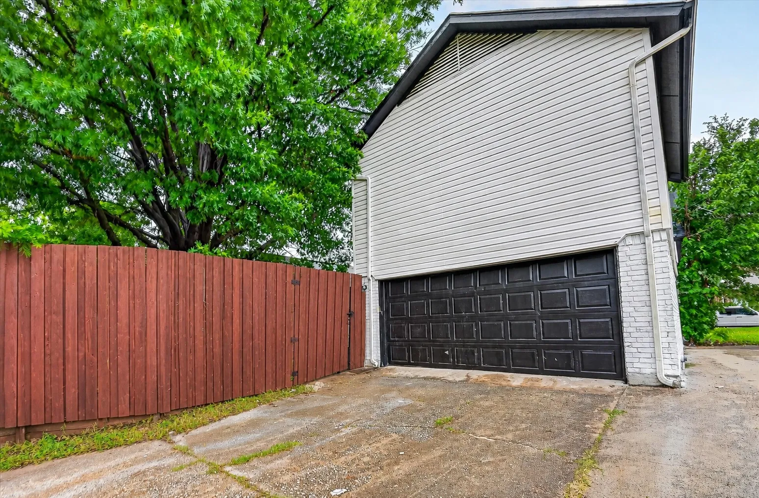 Detached garage with a paneled door, gray siding, and white brick accents
