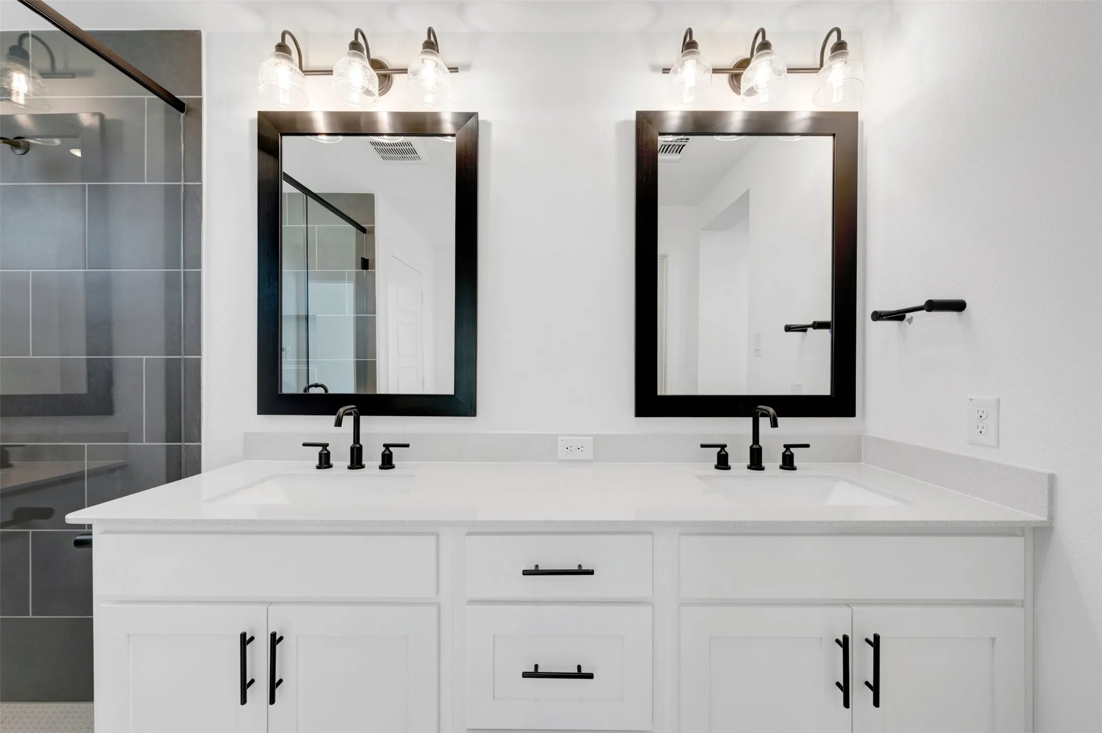 Dual vanity with white cabinetry and matte black hardware, under-mount sinks, and framed mirrors