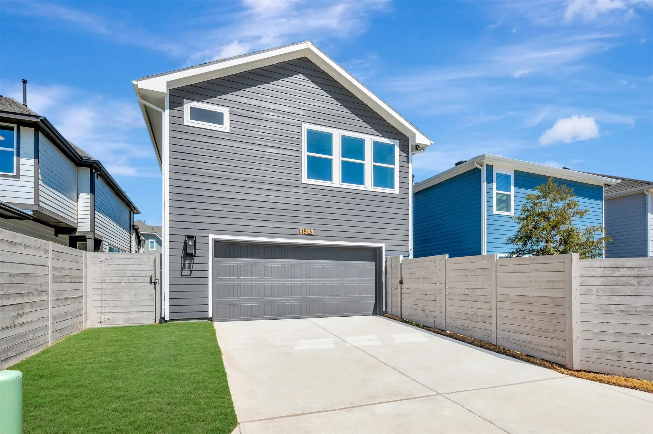 Contemporary exterior with horizontal siding, an attached garage, a concrete driveway, a side yard with grass, and a privacy fence