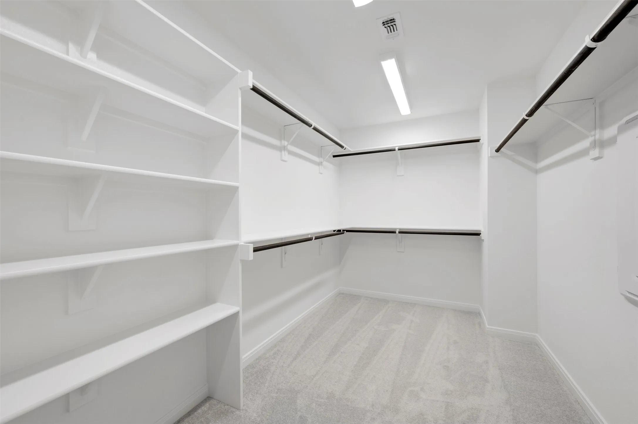 Walk-in closet featuring extensive built-in shelving, multiple hanging rods, recessed lighting, and carpet flooring