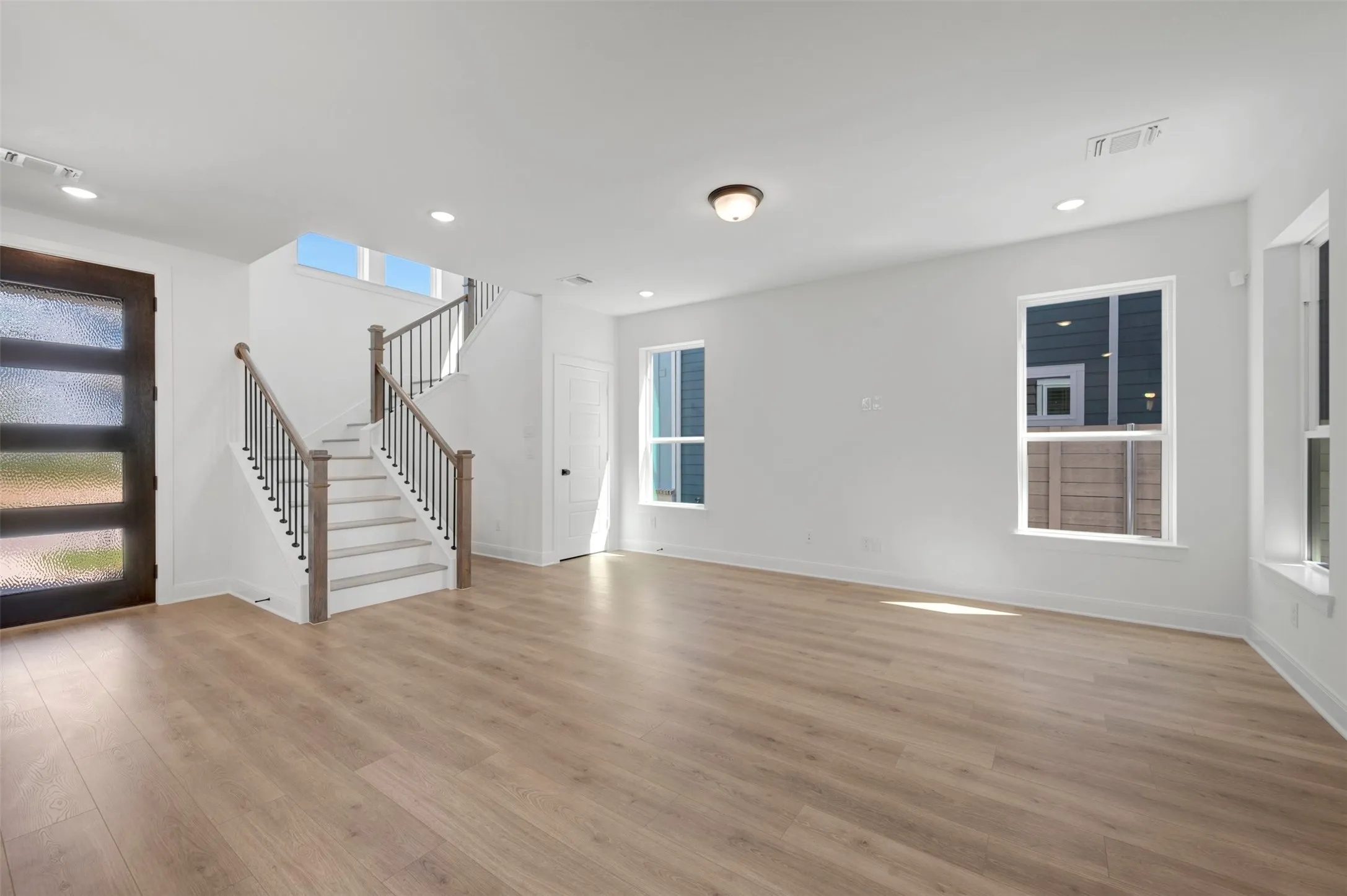 Expansive living area featuring wood-finish flooring, recessed lighting, and multiple windows