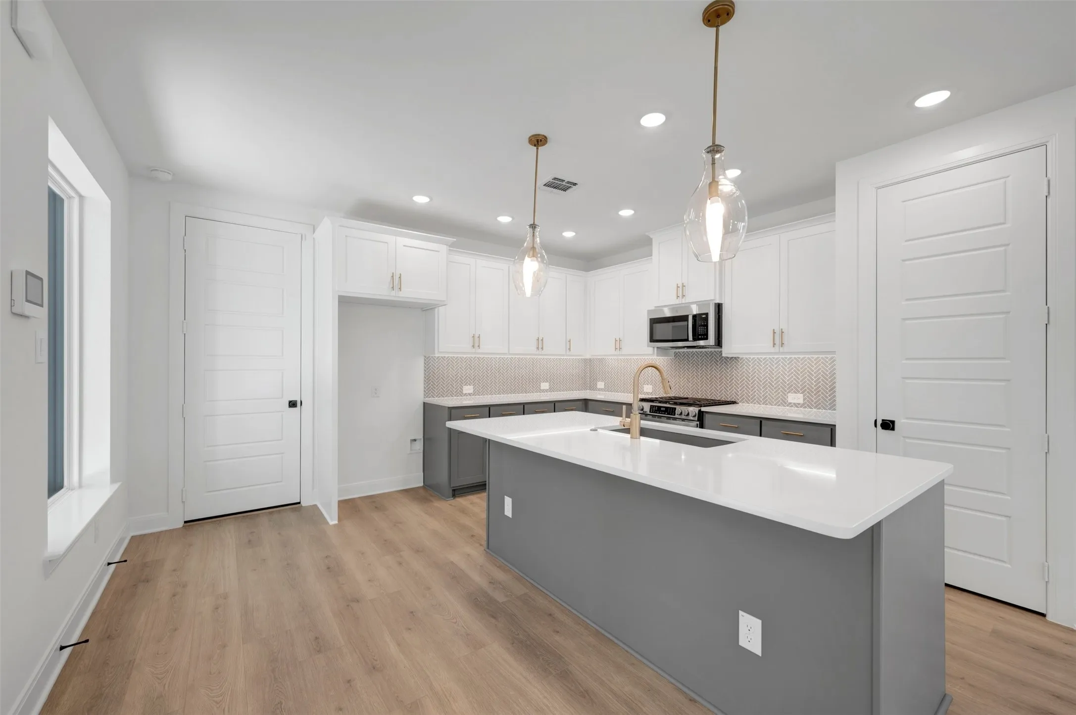 Kitchen featuring wood-finish flooring, two-tone cabinetry, a central island with countertop, a tile backsplash, and recessed lighting