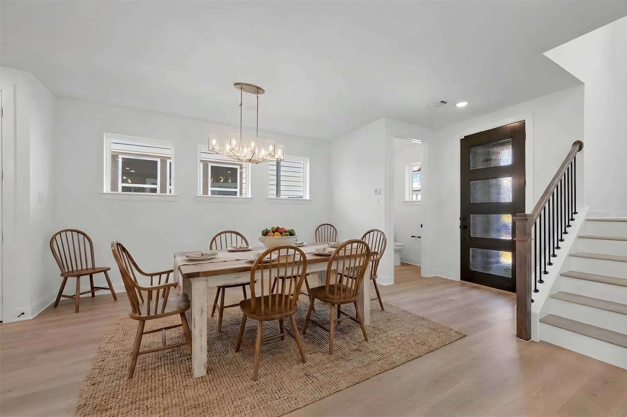 Dining area with light wood-finish flooring, a contemporary chandelier, and multiple windows