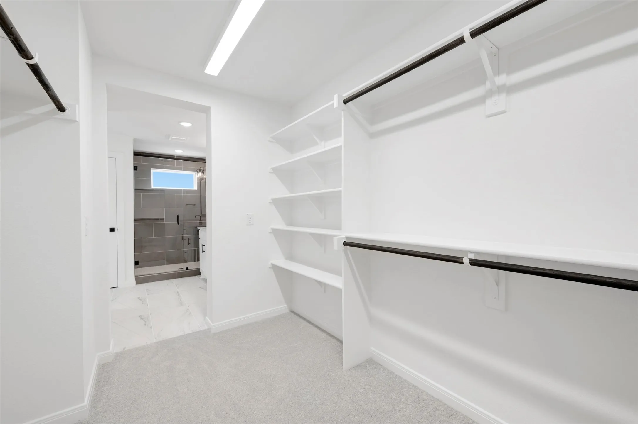 Spacious closet with built-in shelving, dual hanging rods, and light gray carpeting