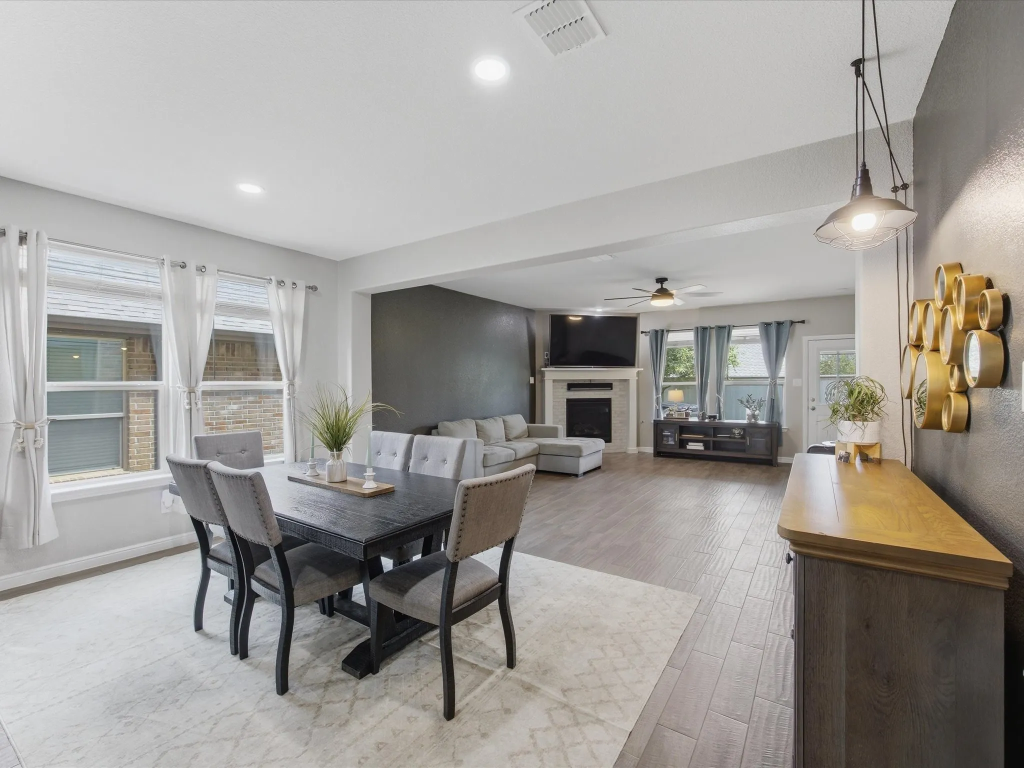 Open-concept living and dining areas featuring wood-finish flooring, recessed lighting, and ample natural light from multiple windows.