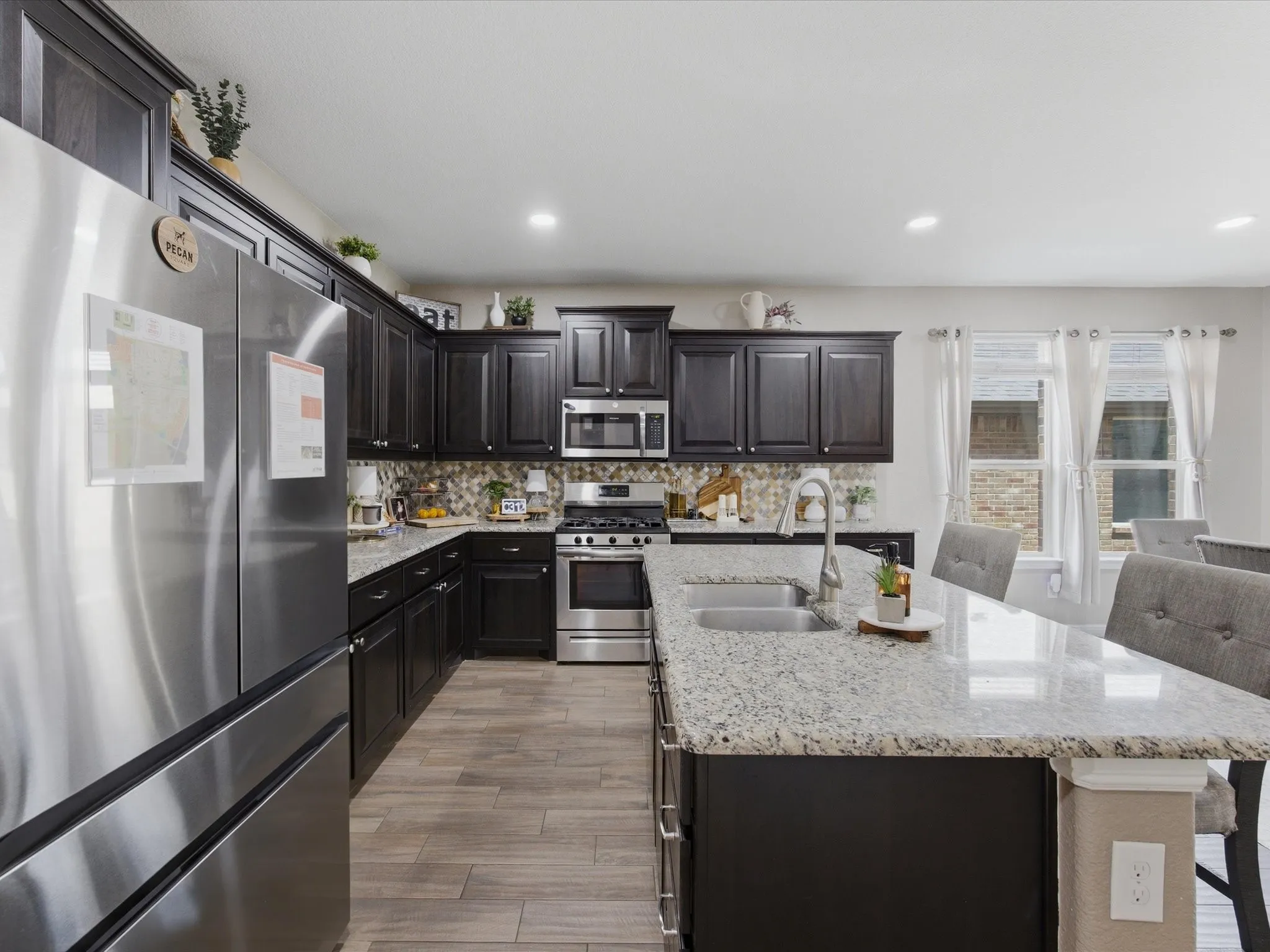 Modern kitchen featuring dark wood cabinetry, stainless steel appliances, granite countertops, and wood-finish​​‌​​​​‌​​‌‌​‌‌​​​‌‌​‌​‌​‌​​​‌​​ flooring