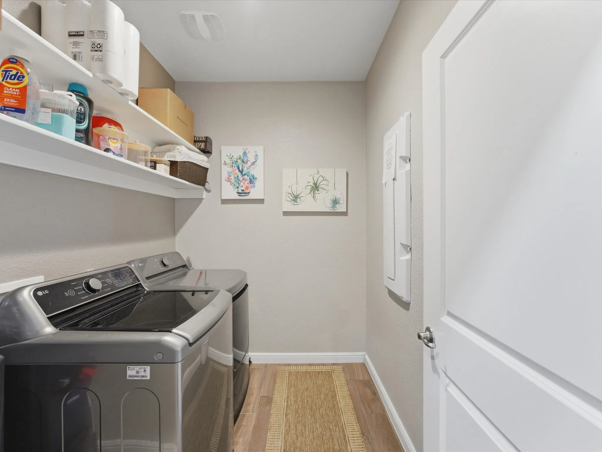 1st floor. Dedicated laundry space featuring wood-finish flooring, white built-in shelving, and light neutral wall tones