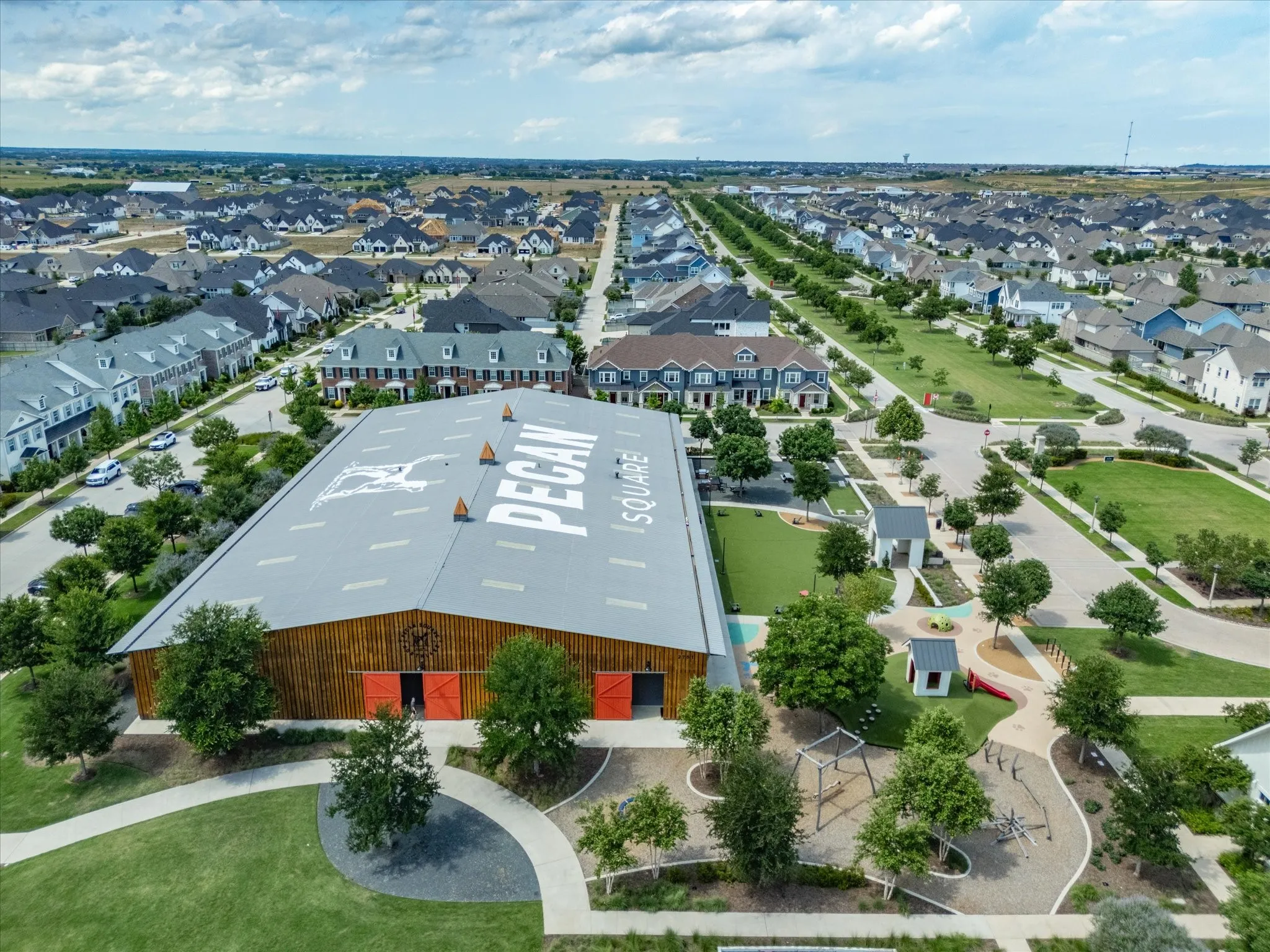 Community amenity building featuring a metal roof with branding, wood siding, and large red barn doors