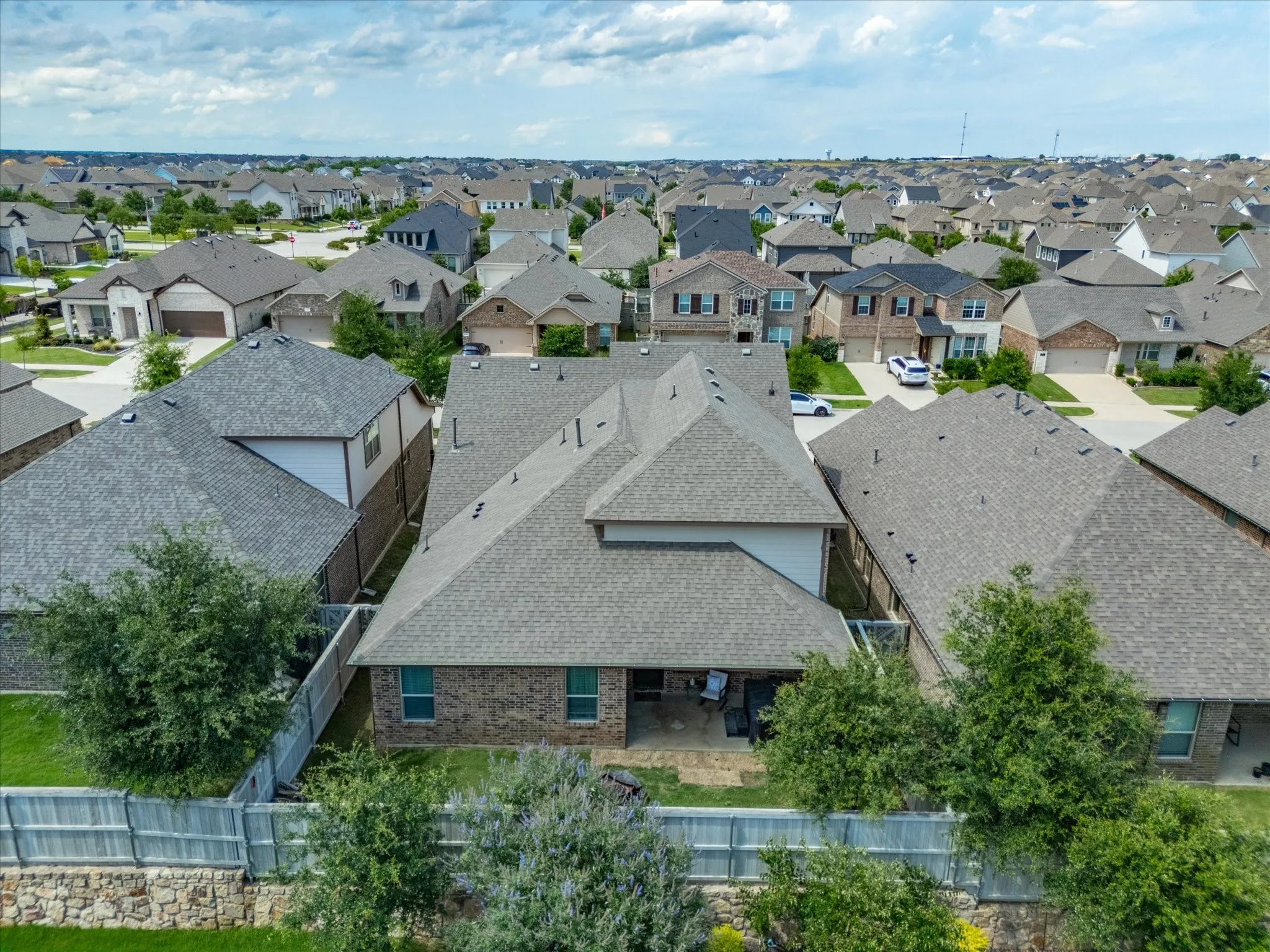 Rear elevation featuring a covered patio, brick and siding exterior, and a private fenced yard with mature trees