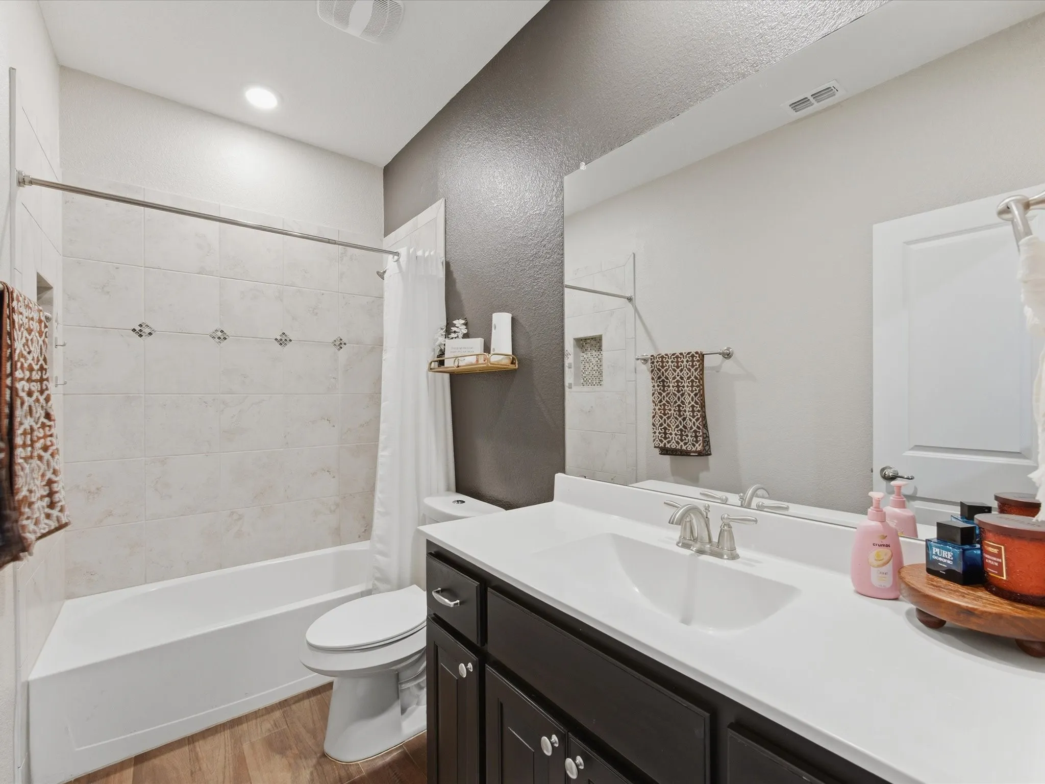 1st floor, Bathroom featuring a dark wood-finish vanity with an integrated sink, a full-width mirror, and a tiled shower-tub combination with an inset niche