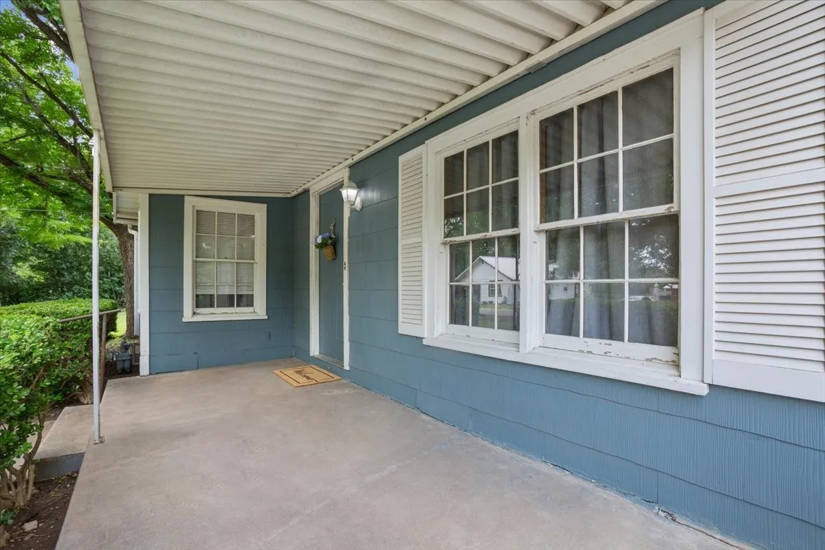 Covered front porch featuring a smooth concrete slab and white metal awning
