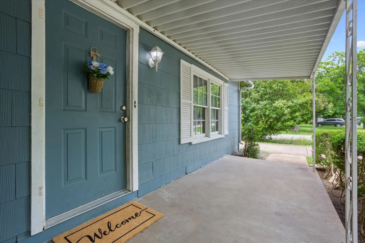 Covered front porch featuring a paneled entry door, horizontal siding, and a decorative wall-mounted light fixture