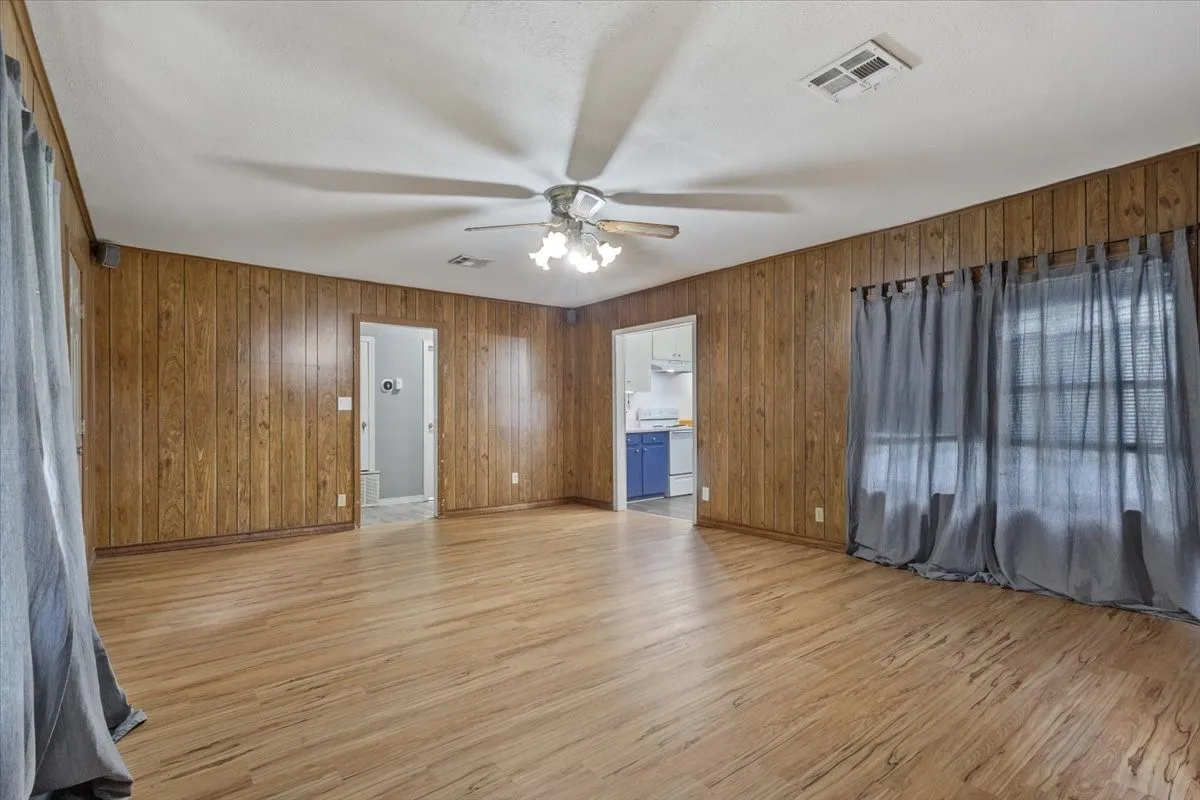 Spacious room featuring wood-finish paneling, a neutral ceiling, and wood-finish flooring