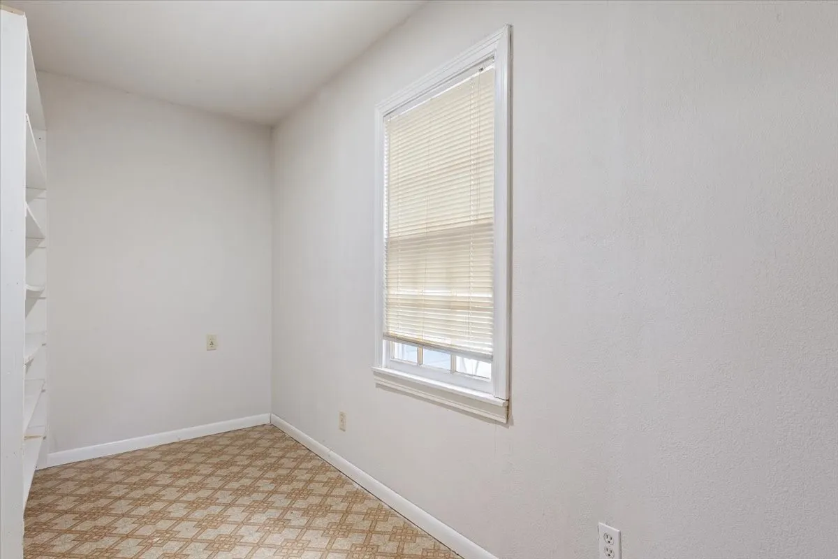Room featuring built-in shelving, a single window with blinds, and geometric patterned flooring