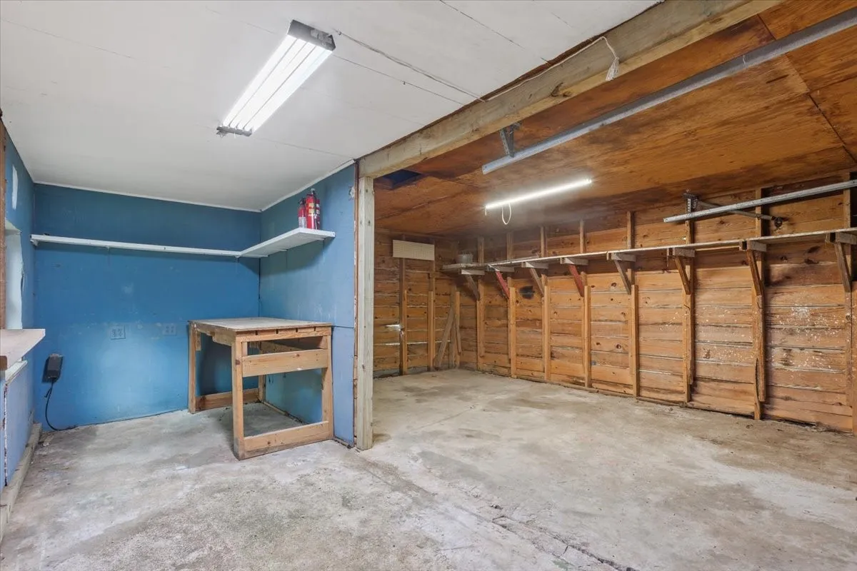 Utility space featuring concrete flooring, a painted blue wall, and built-in wood shelving