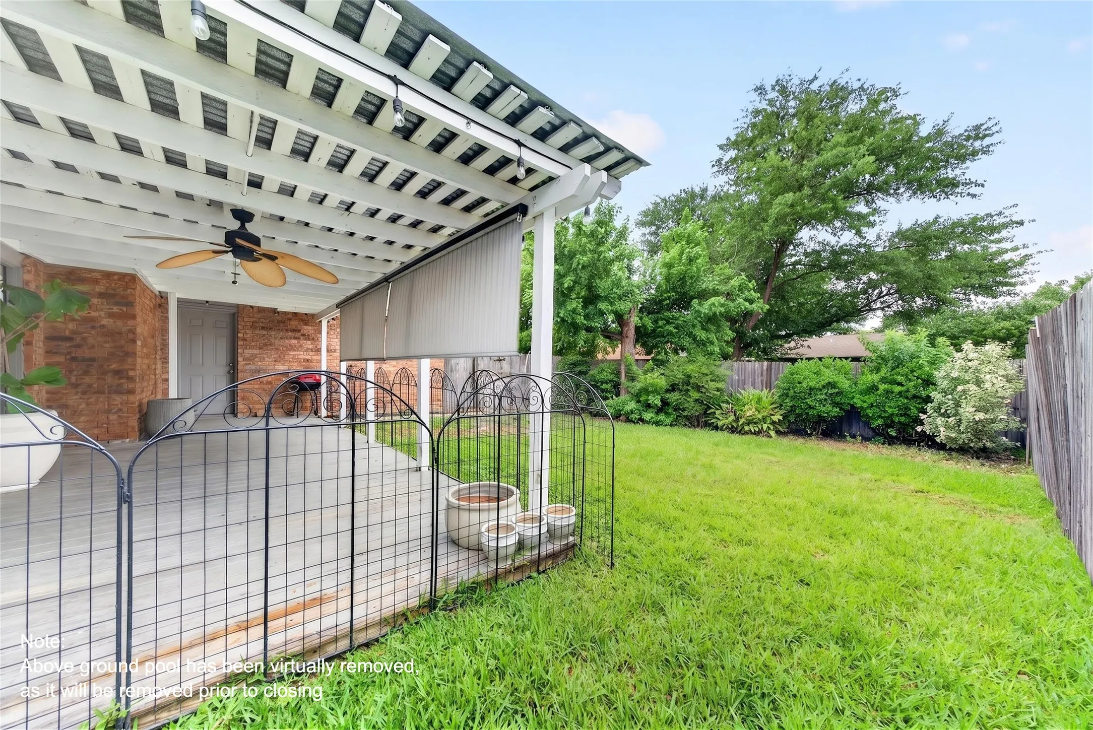 Covered back patio with a ceiling fan, brick exterior, wood-finish decking, and string lighting
