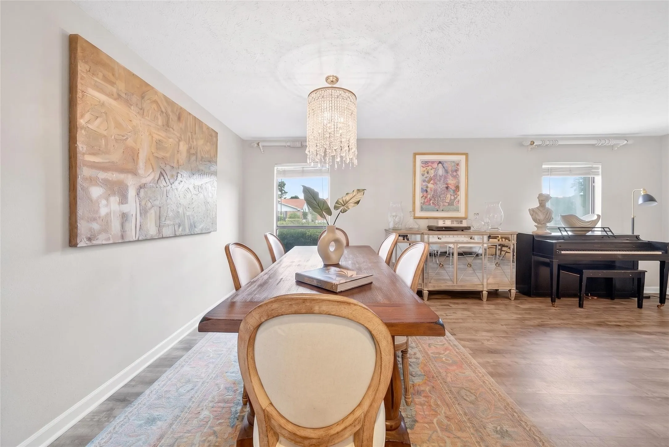 Formal dining space featuring wood-finish flooring, a crystal chandelier, and ample natural light from two windows