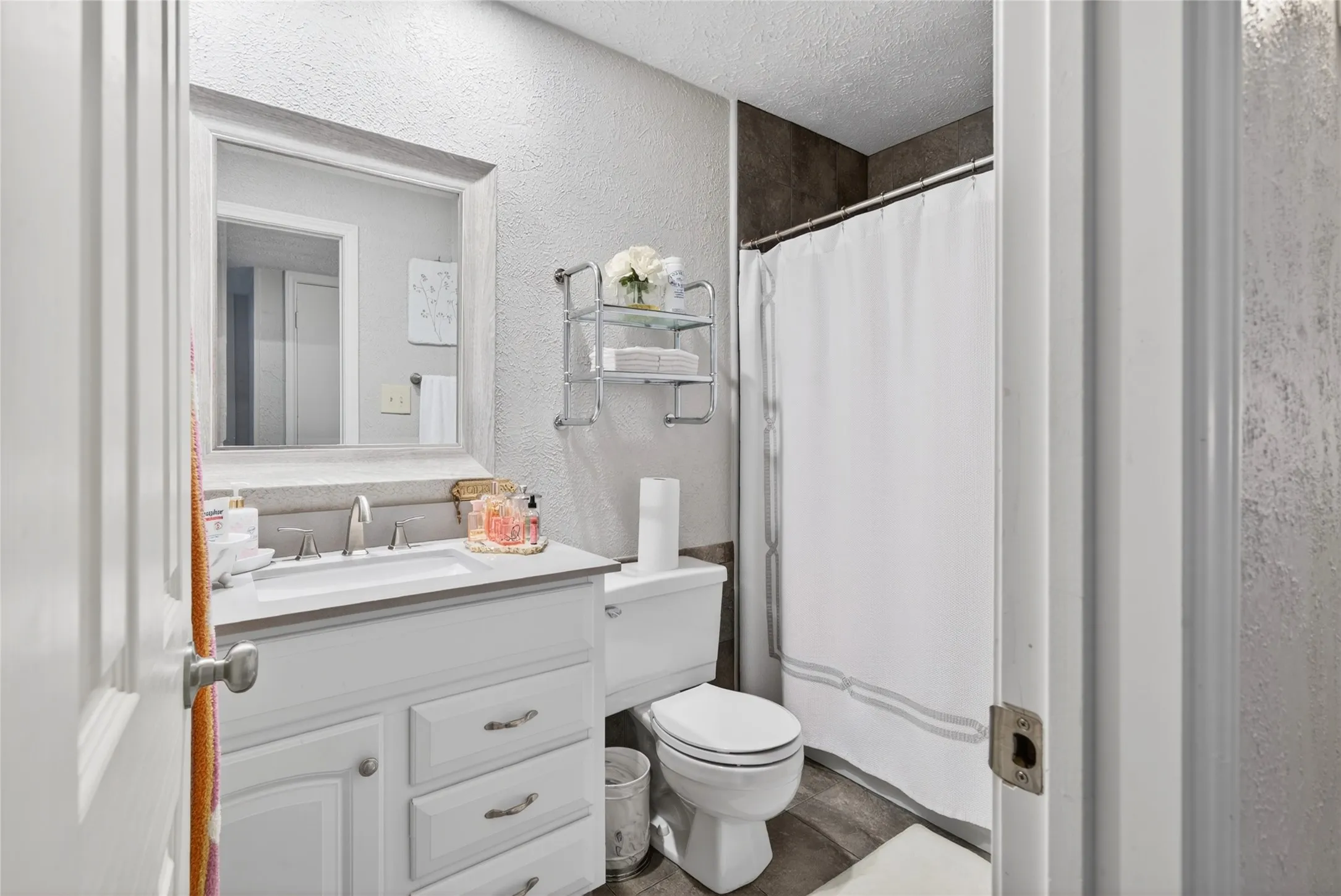 Bathroom featuring a white vanity with a rectangular sink, a framed mirror, and a shower with a white curtain