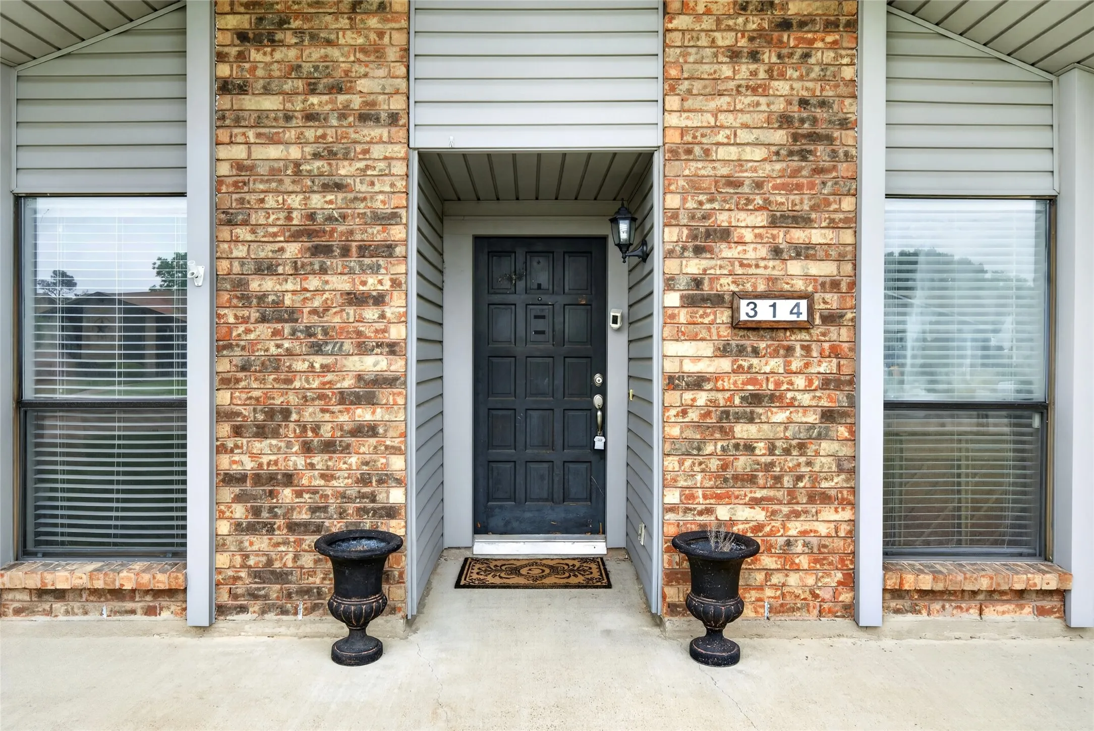 Entryway with brick facade and gray siding accents