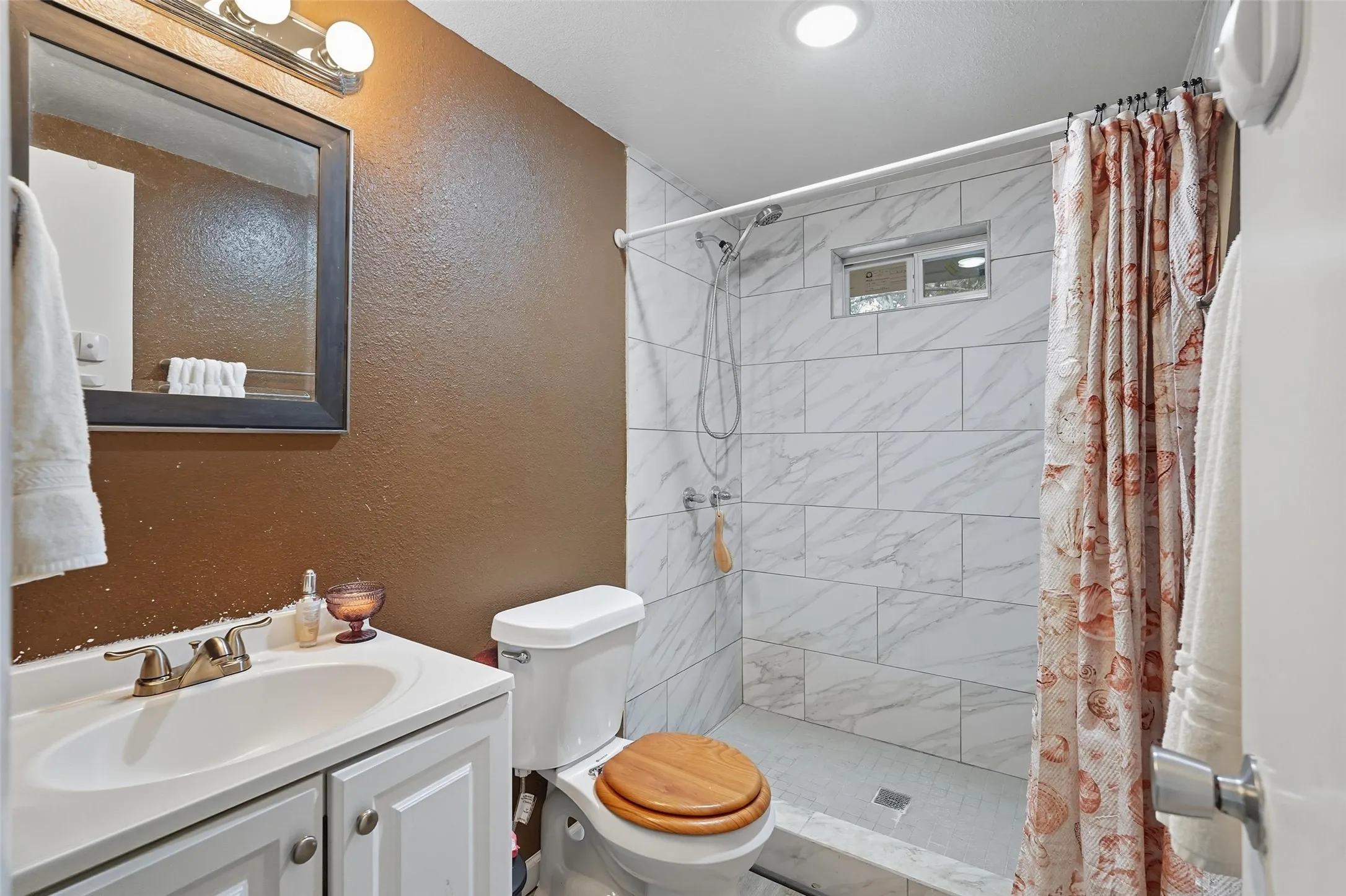 Bathroom featuring a walk-in shower with white tiled walls and a recessed window