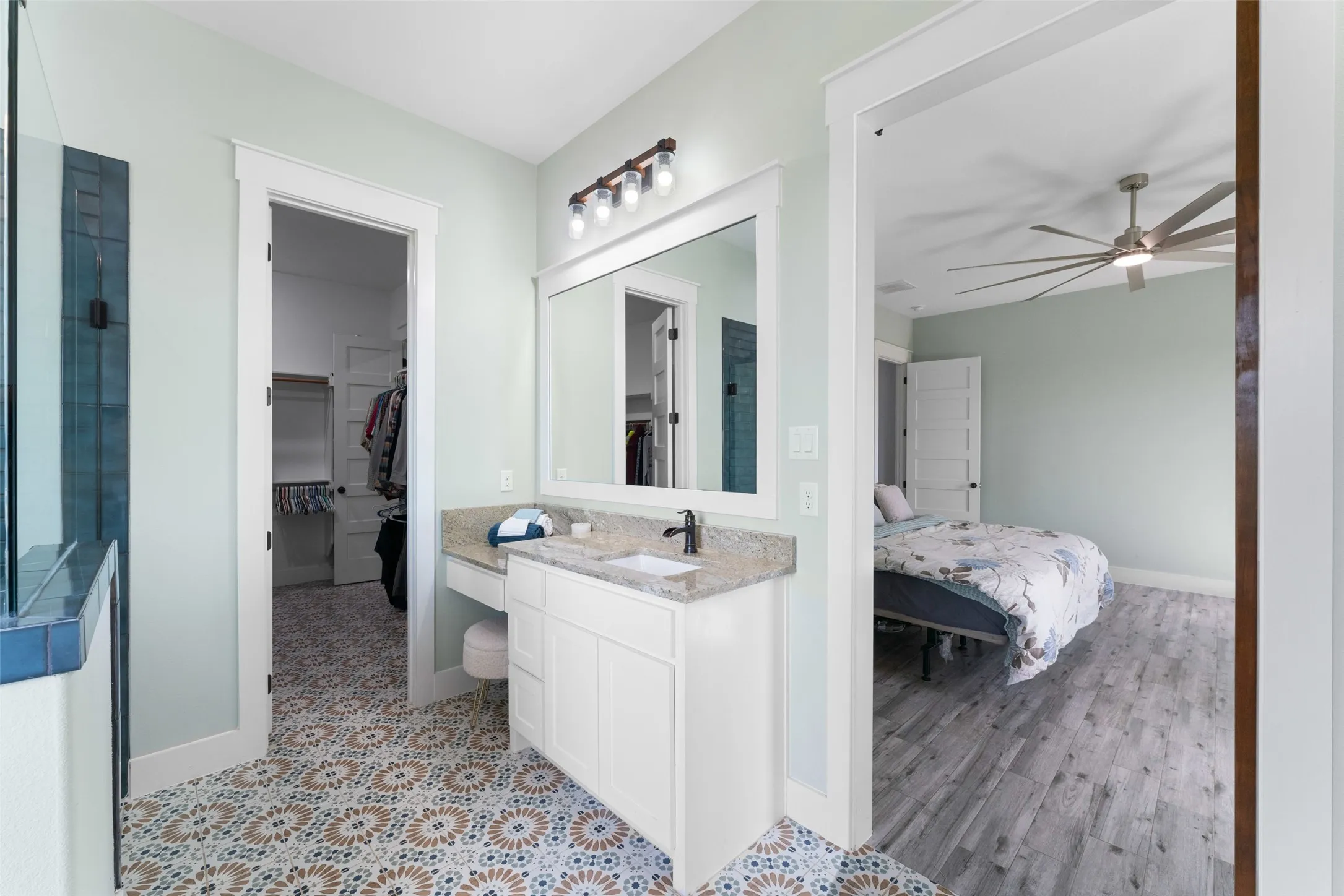 Bathroom featuring a single vanity with granite countertop, an integrated sink, and white cabinetry