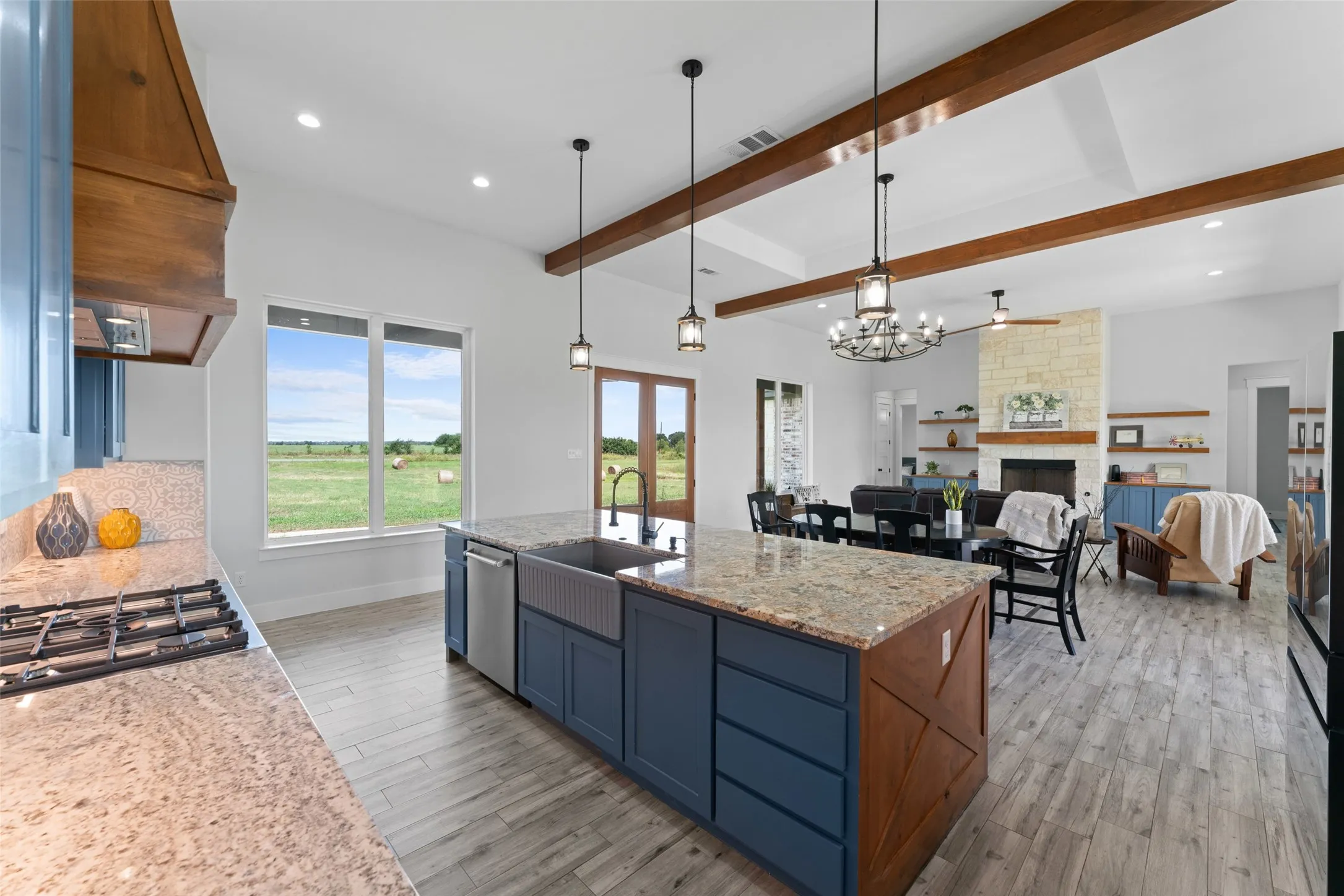 Spacious kitchen featuring a large island with granite countertops, an integrated farmhouse sink, and a stainless steel dishwasher