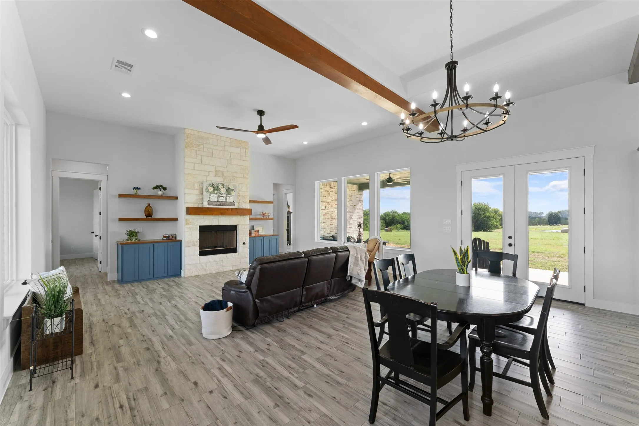 Spacious living area featuring wood-finish flooring, a stone fireplace with a wood mantle, and built-in shelving