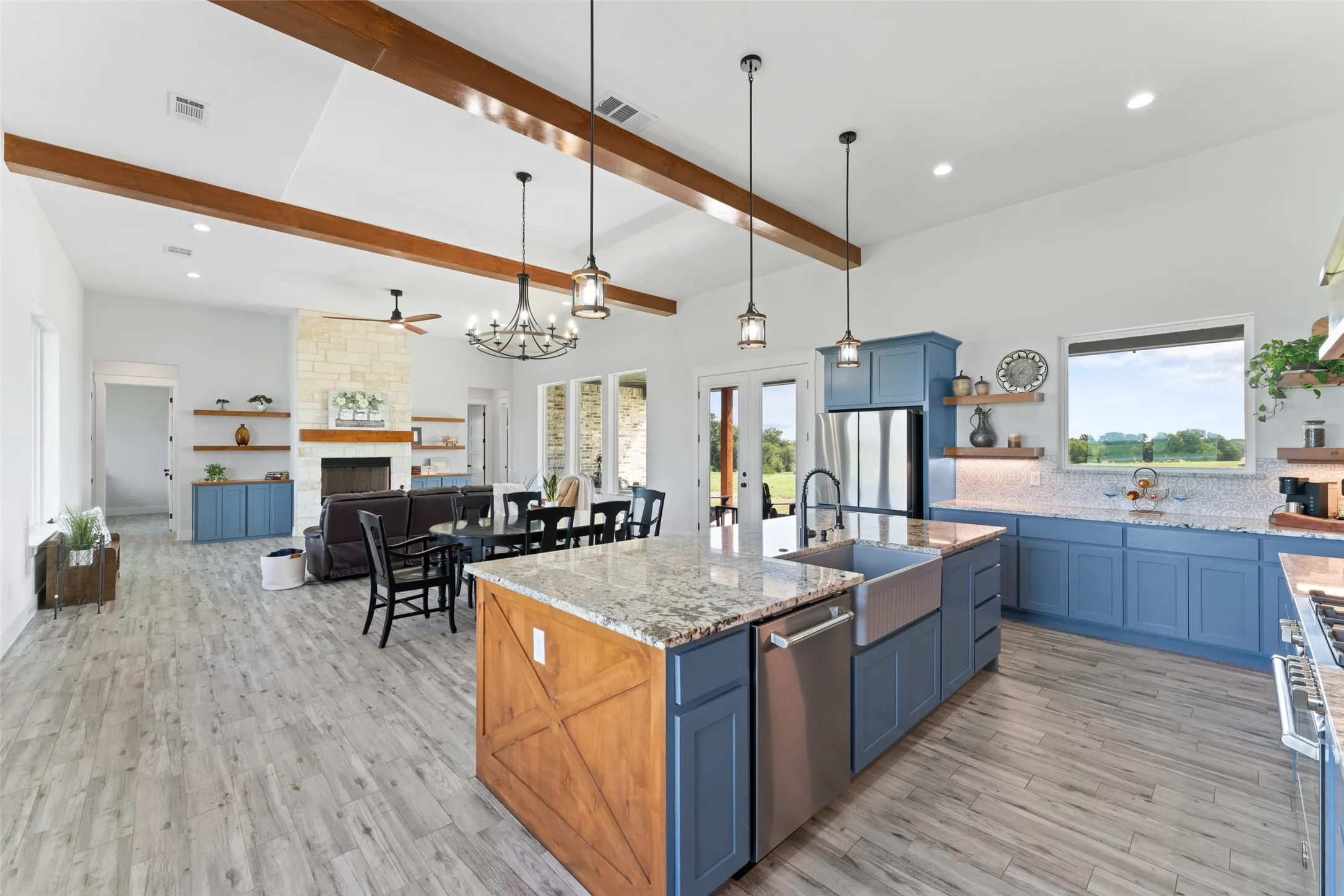 Expansive kitchen and living area featuring a large center island with a farmhouse sink, stainless steel appliances, and blue cabinetry