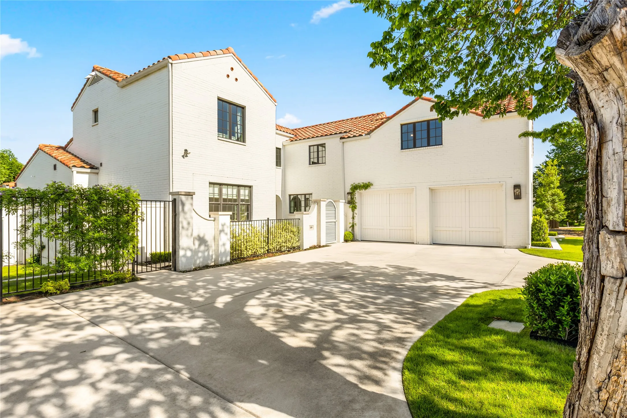Elegant Spanish Mediterranean style home with striking white-painted brick, clay tile roofing, and beautifully maintained landscaping that creates exceptional curb appeal. A gated courtyard entry, expansive driveway, and oversized two-car garage complete this sophisticated and inviting exterior.