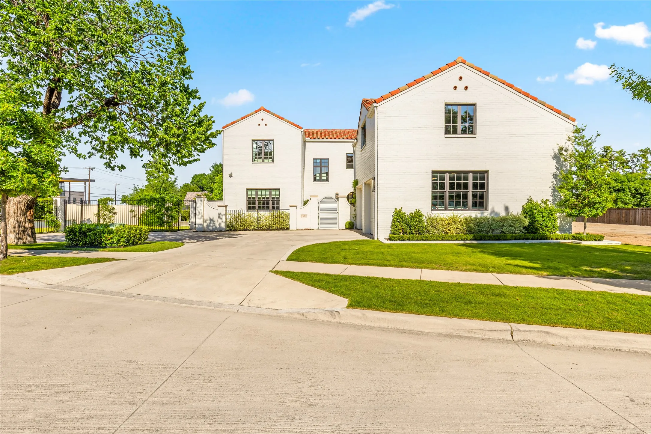Elegant Spanish Mediterranean style home with striking white-painted brick, clay tile roofing, and beautifully maintained landscaping that creates exceptional curb appeal. A gated courtyard entry, expansive driveway, and oversized two-car garage complete this sophisticated and inviting exterior.