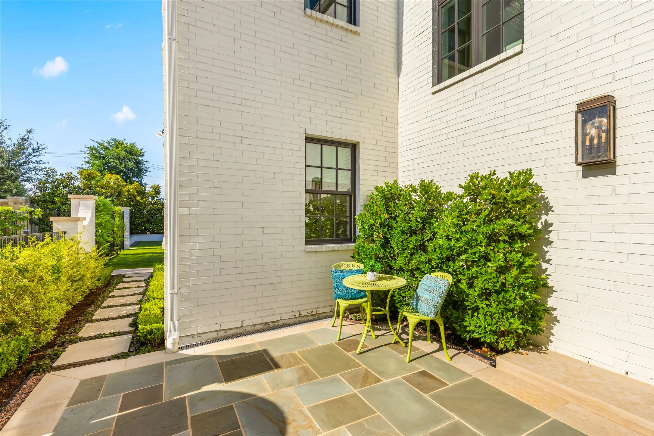 Charming front patio entry features intimate outdoor seating and stone steps that lead seamlessly to the backyard, creating a warm and inviting outdoor flow.