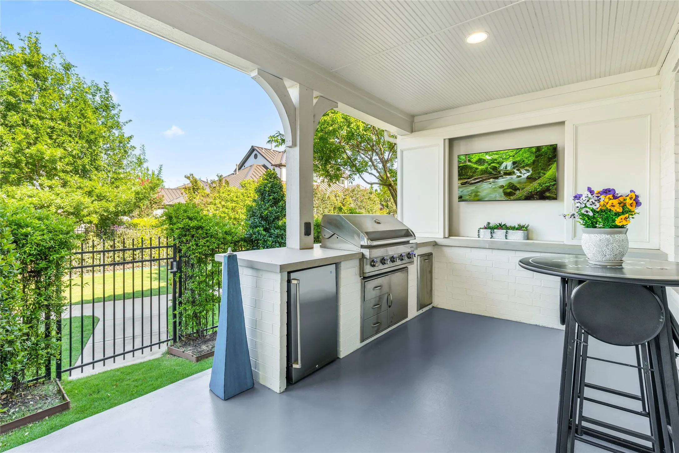 Outdoor kitchen and covered patio create an ideal entertaining space with built in grilling, bar seating, and peaceful views of the surrounding greenery.
