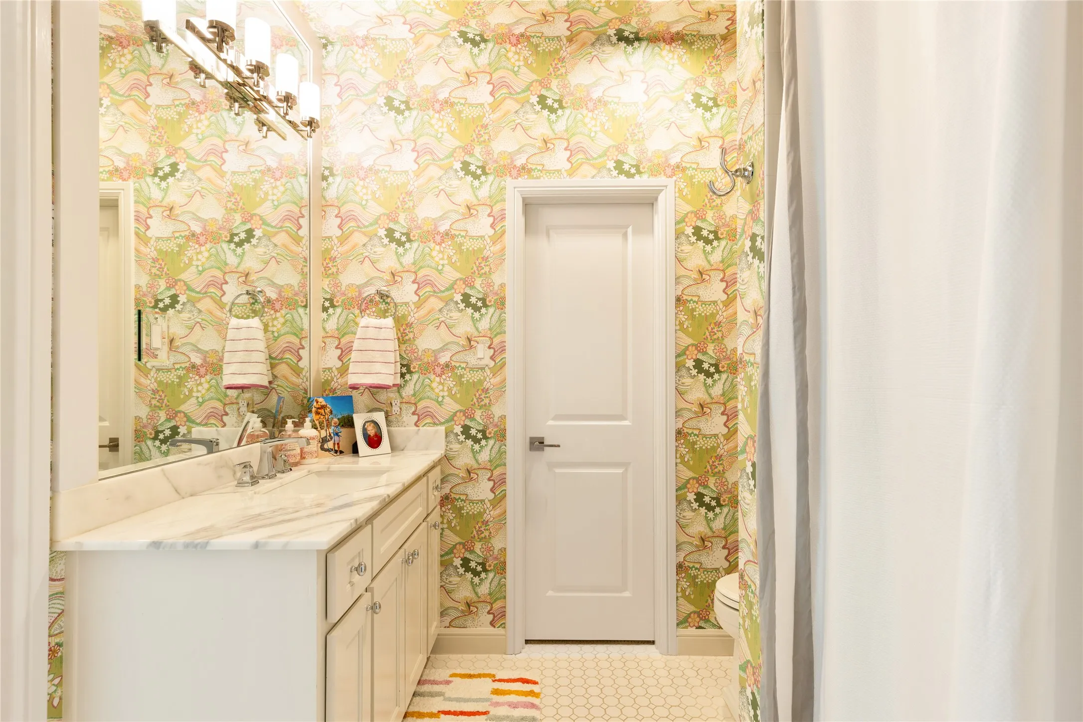 Elegant bathroom showcases designer wallpaper, refined finishes, and timeless details that add charm and sophistication to the home.