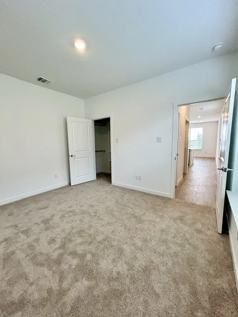 Spacious room featuring neutral-toned carpet flooring and white painted walls