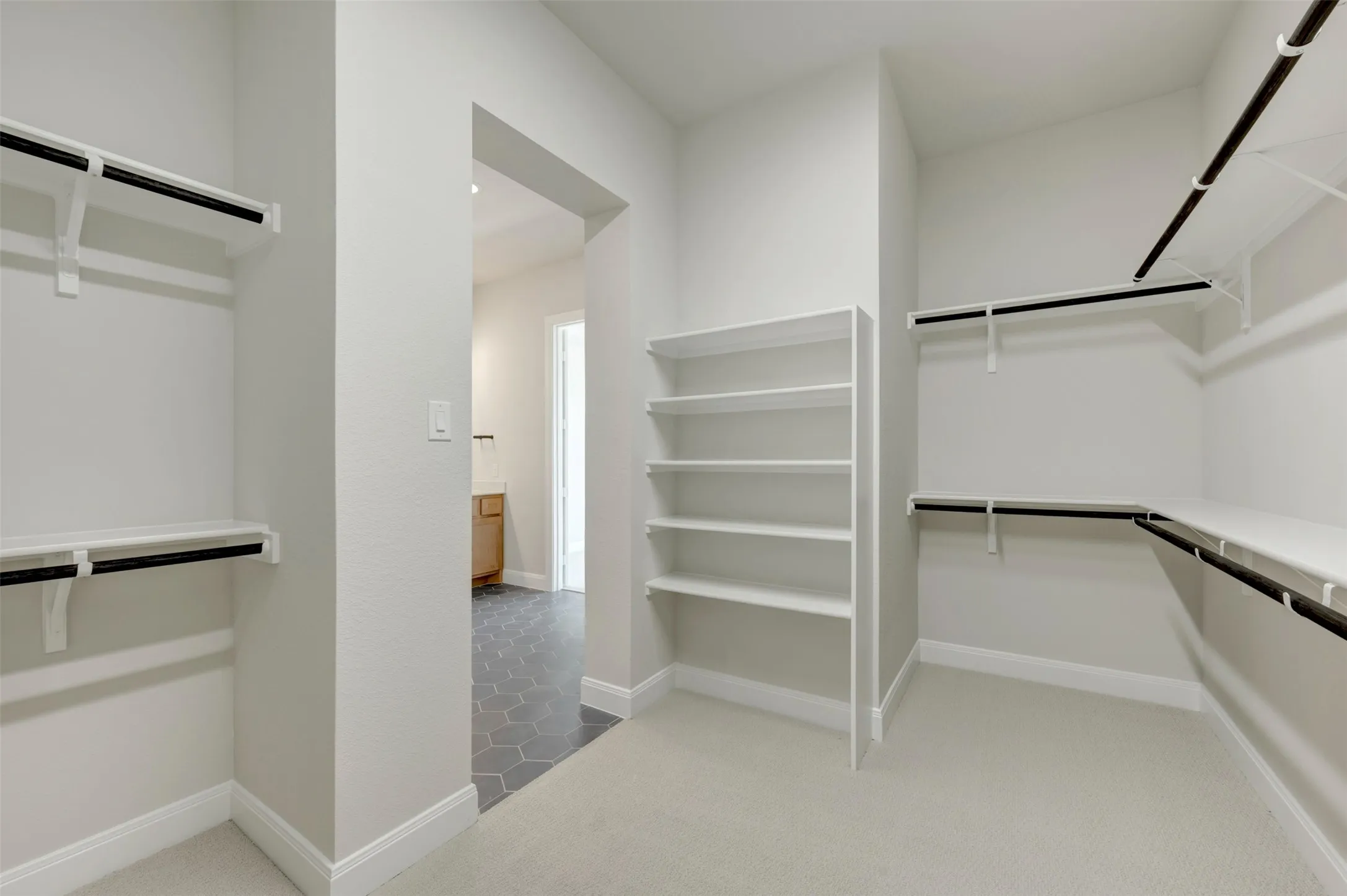Spacious walk-in closet with carpeted flooring, extensive shelving, and multiple hanging rods