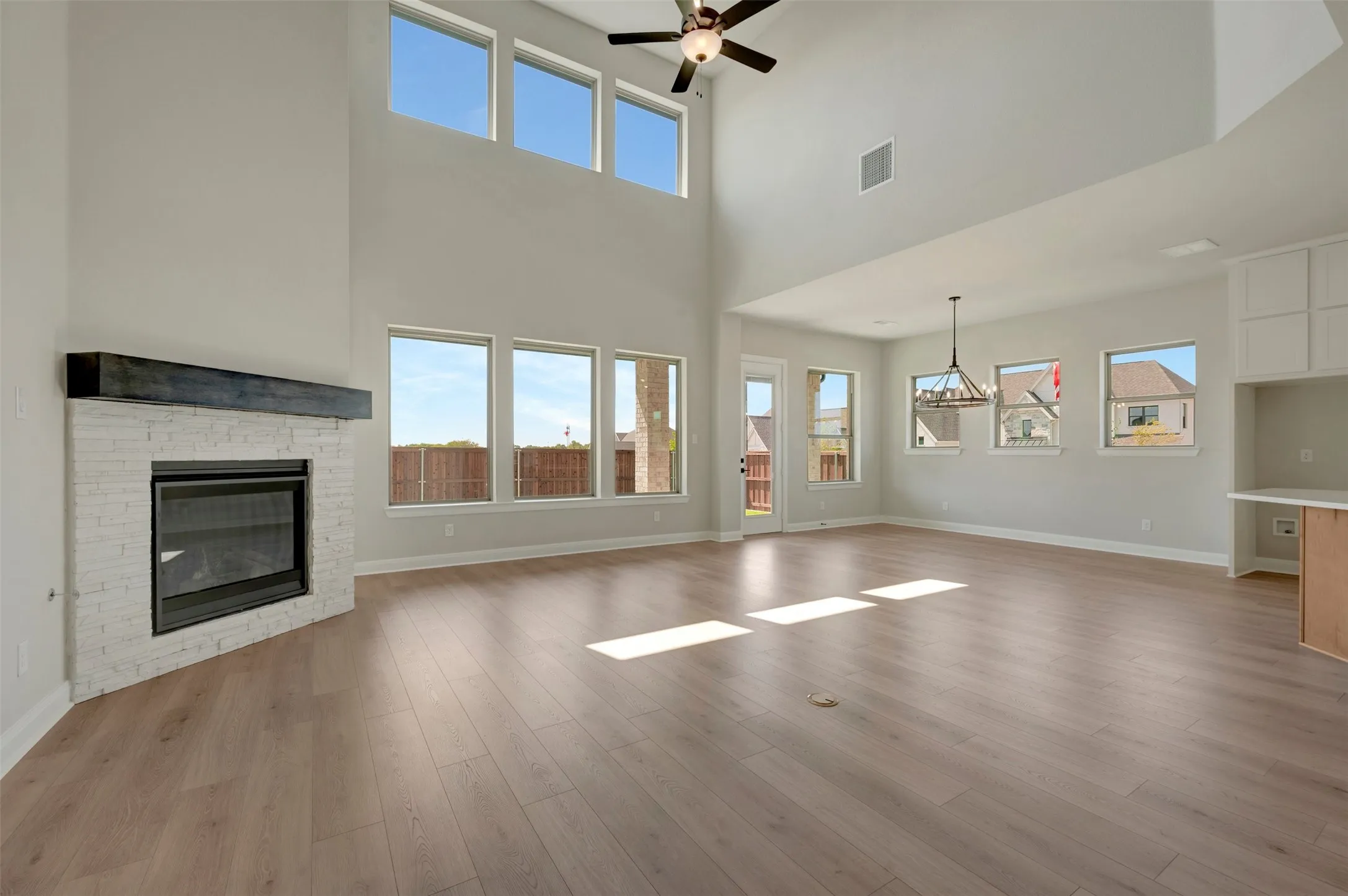Vaulted ceilings, wood-finish flooring, white brick fireplace with dark wood mantel, built-in cabinetry, and multiple windows
