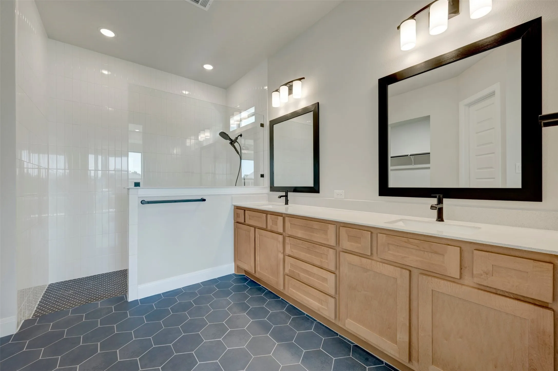 Double vanity with light wood-finish cabinetry, white countertops, and matte black fixtures