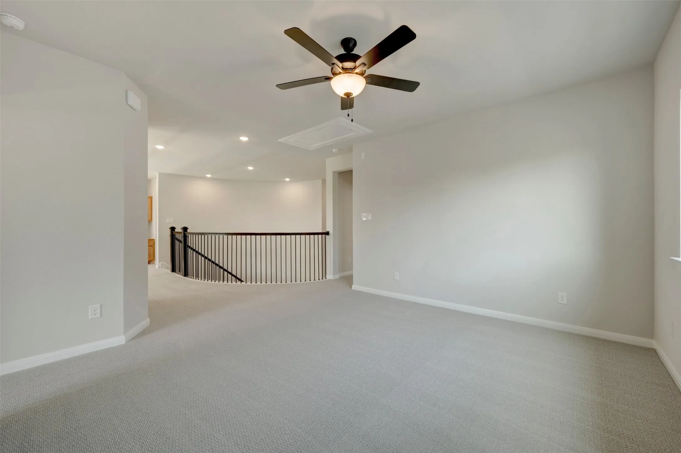 Recessed lighting, ceiling fan, carpeting, and a railing with dark balusters
