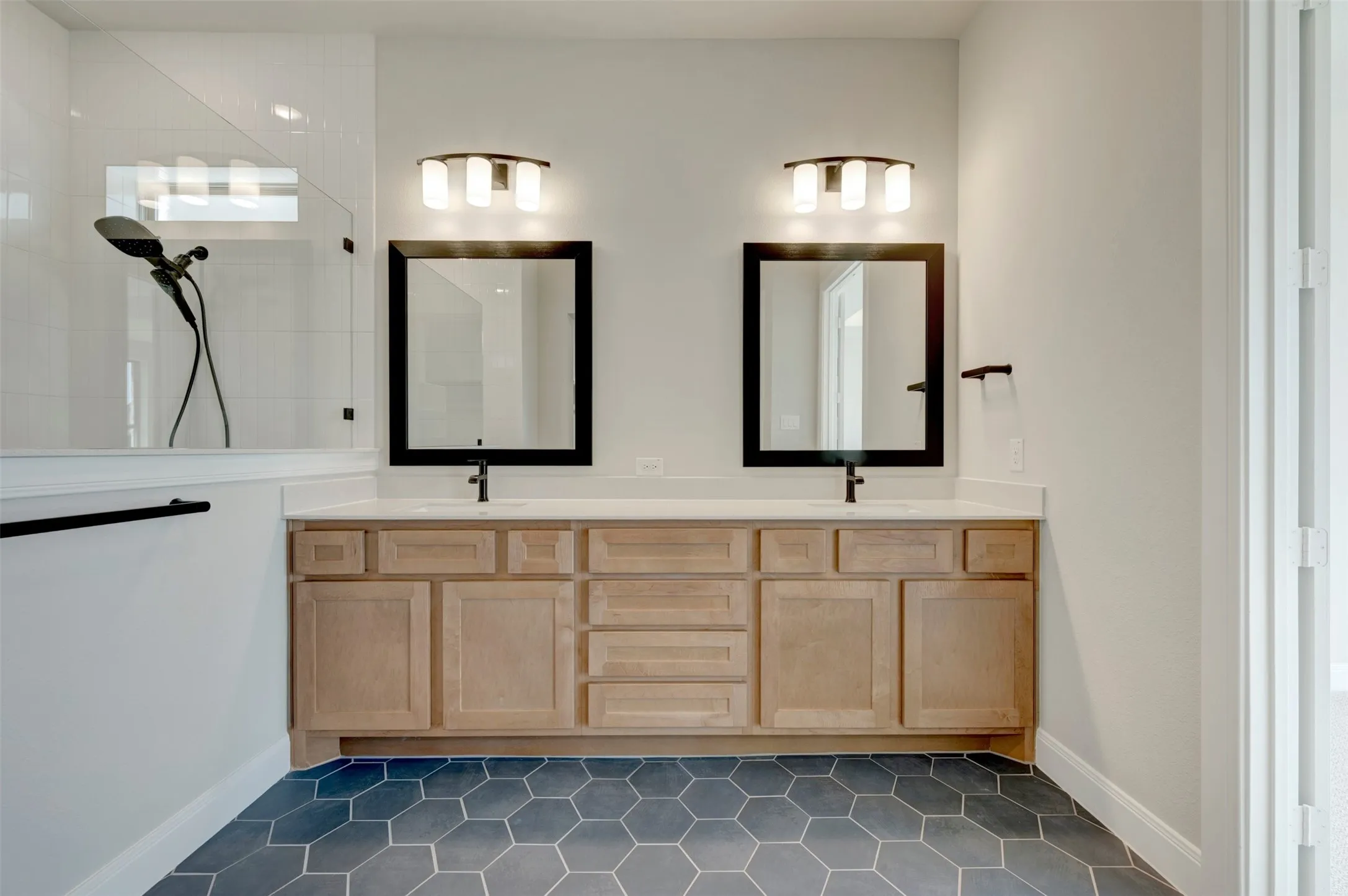 Dual vanity with light wood-finish cabinetry and white countertops