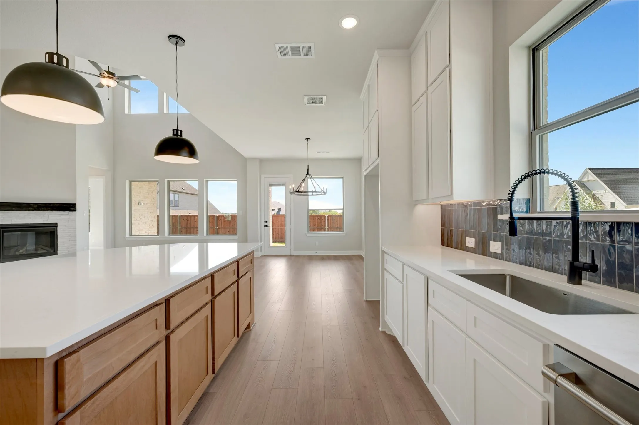 Open-concept living area with vaulted ceiling, wood-finish flooring, and a fireplace with a tile surround