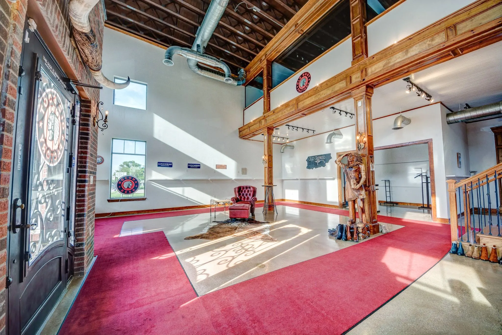 Grand entrance featuring an ornate iron and glass door, exposed brick wall, and two-story vaulted ceiling