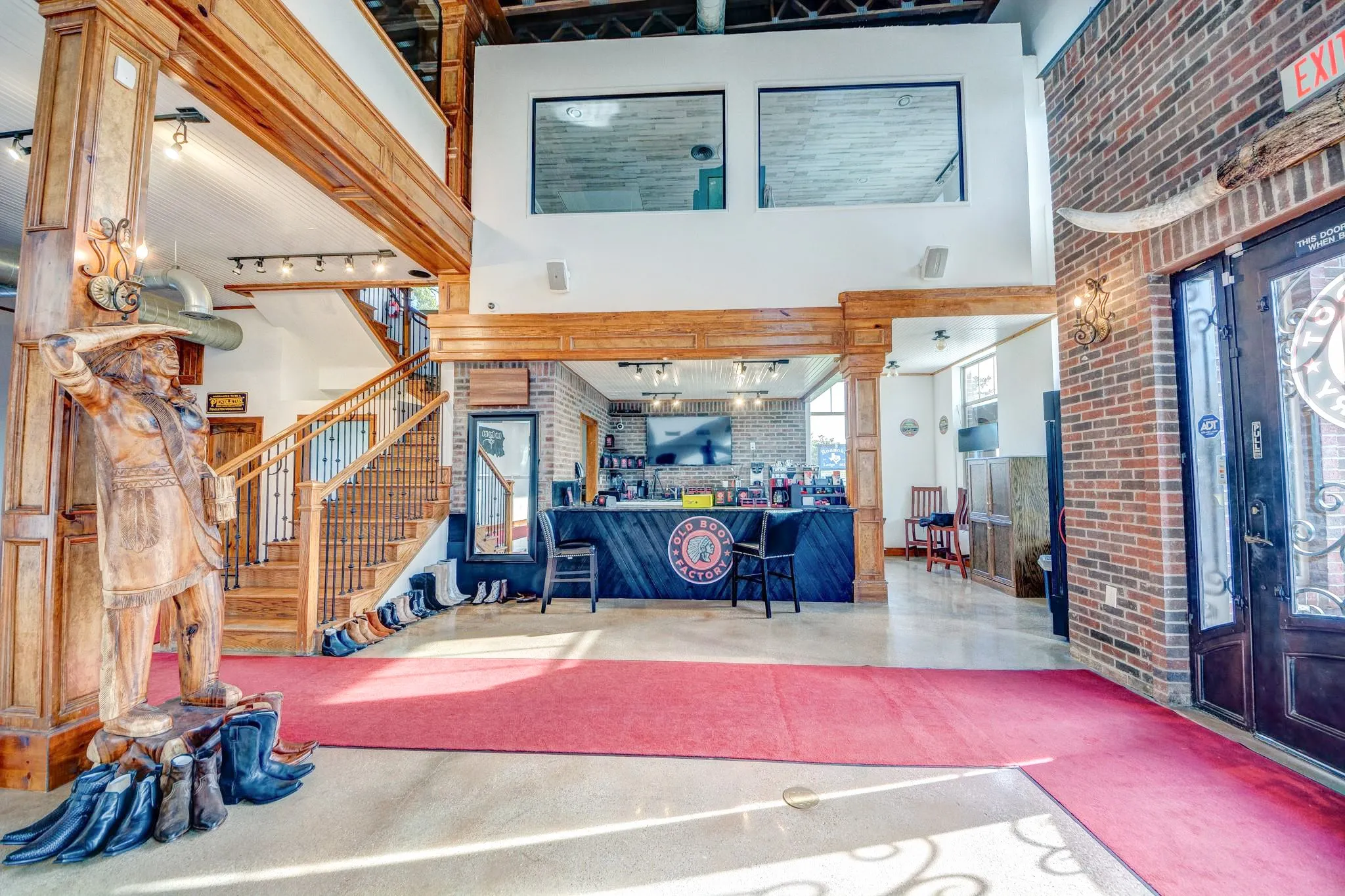 Spacious interior featuring exposed brick walls, a prominent wooden staircase with wrought iron balusters, and substantial wood beams