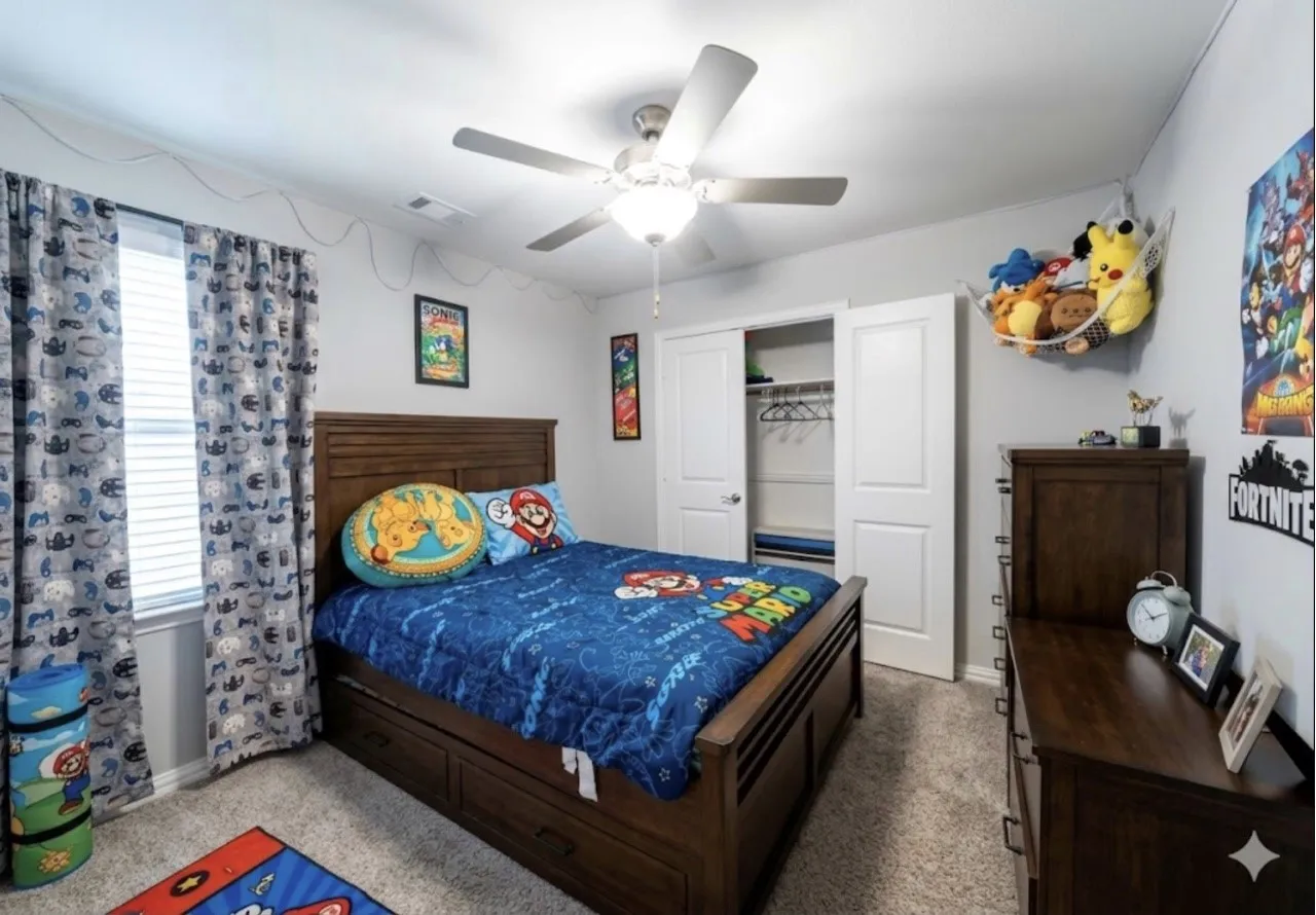 Carpeted room featuring a ceiling fan with integrated lighting, a window with blinds and curtains, and a two-door closet with shelving and hanging space