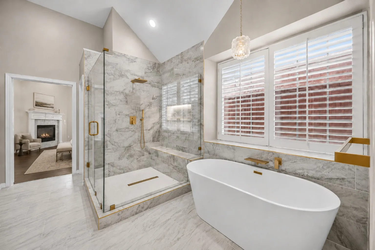 Luxurious bathroom featuring a spacious walk-in shower with a built-in bench, a freestanding soaking tub with a wall-mounted faucet, plantation shutters, and a vaulted ceiling